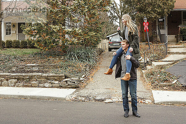 Ein Teenager-Bruder trägt seine lachende Schwester auf seinen Schultern auf der Straße