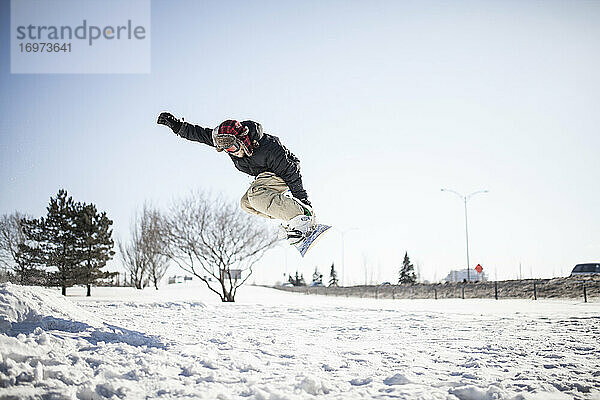 Junger Snowboarder in der Luft beim Sprung