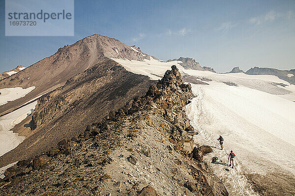 Zwei Wanderer klettern in der Morgendämmerung auf den Gipfel des Glacier Peak.