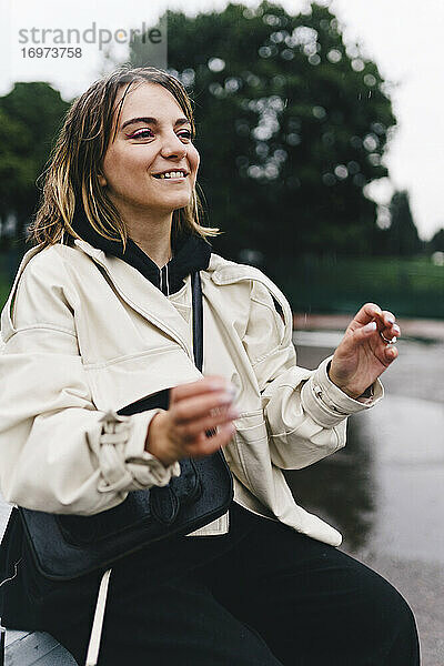 Glücklich lächelnde Frau im Regen sitzend