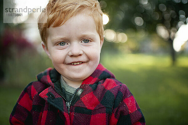 Nahaufnahme eines kleinen Jungen im Wintermantel  der lächelnd nach draußen geht