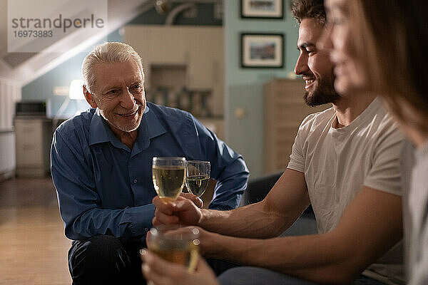 Fröhlicher älterer Mann trinkt Wein mit einem jungen Paar