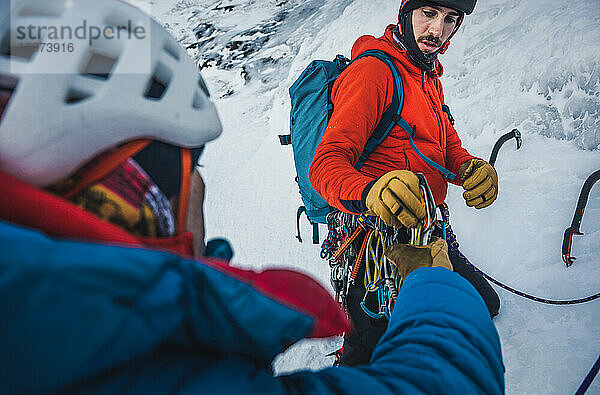 Zwei männliche alpine Eiskletterer sortieren und tauschen ihre Eis- und Felsausrüstung