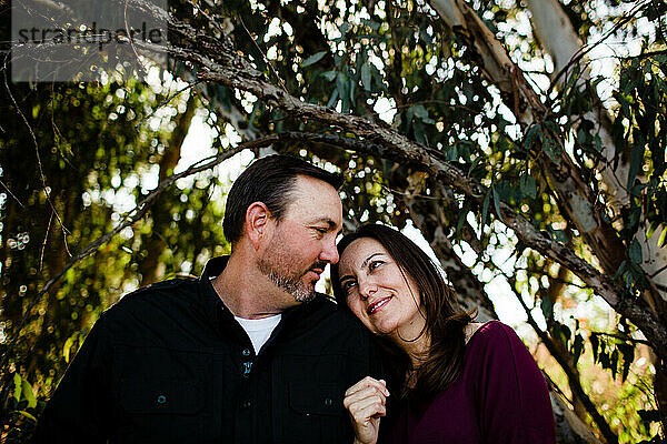 Ehemann und Ehefrau posieren unter einem Baum im Park in Chula Vista