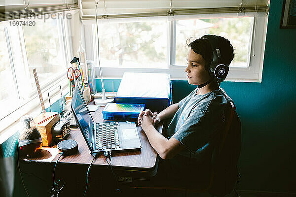 Junge sitzt am ersten Tag der virtuellen Schule an seinem Schreibtisch