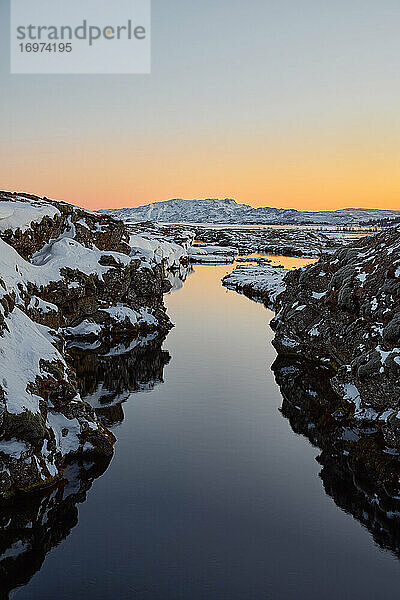 Fjord und schneebedeckte Klippen bei Sonnenaufgang