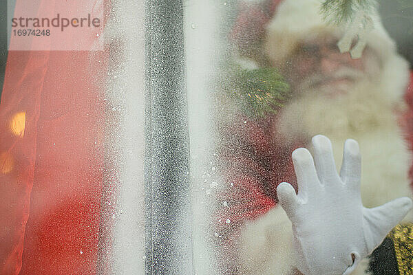 Der Weihnachtsmann streckt die Hand aus  um durch das Fenster eine Verbindung herzustellen