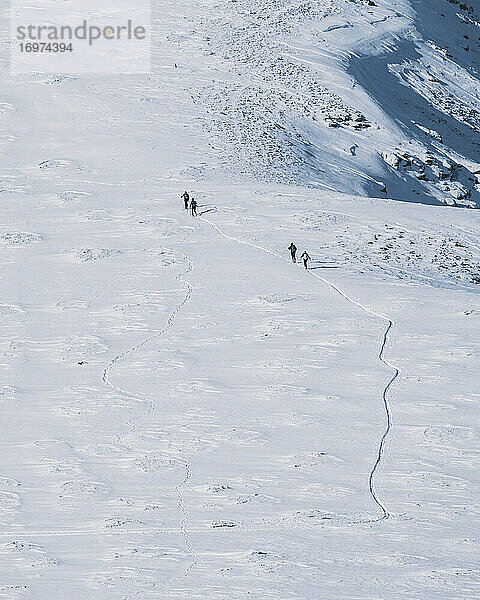 Gruppe von Skiläufern  die den Berg hinauffahren  gegen einen Berggipfel