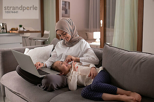 Glückliche muslimische Mutter spielt mit ihrer Tochter während der Arbeit