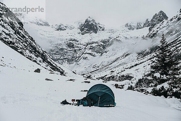 Camping mit blauem Zelt im Winter auf Schnee in der Schweiz