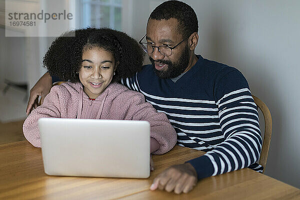 Afrikanisch-amerikanischer Vater und gemischtrassige Tochter am Laptop