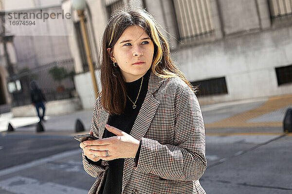 Mädchen mit einem Smartphone in den Händen auf einer Straße in Buenos Aires