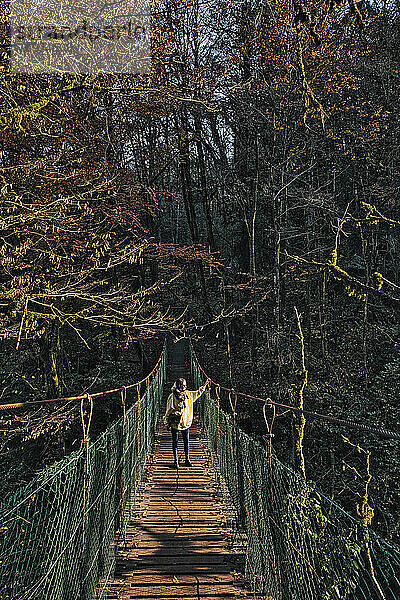 Junge Frau beim Überqueren einer Hängebrücke