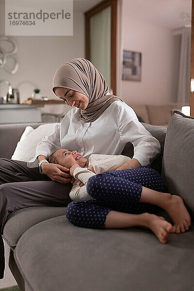 Muslimische Mutter und Tochter spielen auf dem Sofa
