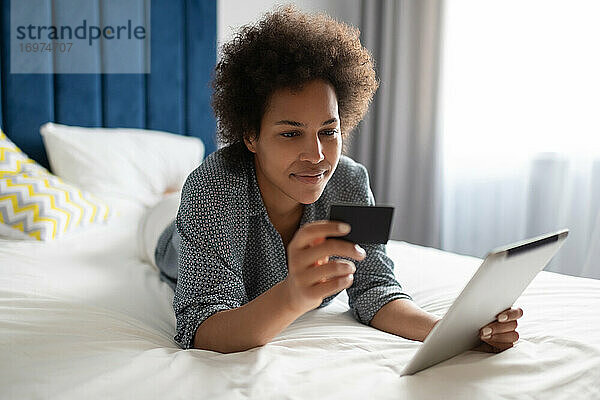 Schwarze Frau beim Online-Shopping mit Tablet
