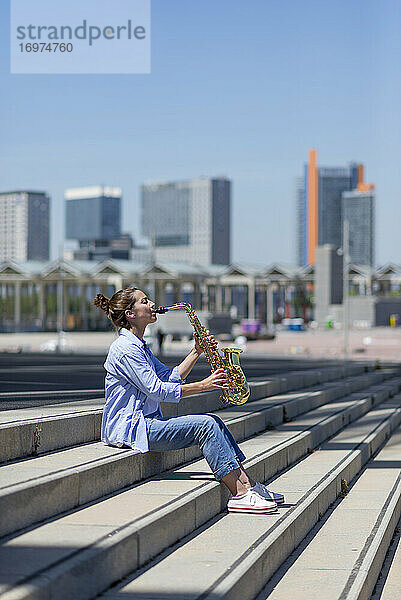 Frau mit Pferdeschwanz  die im Freien stehend ein Saxophon spielt