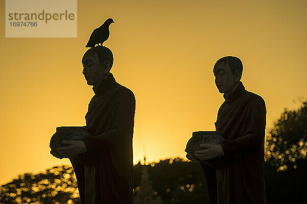 Silhouetten von Mönchsstatuen in der Myo Yar Pyae Pagode bei Sonnenuntergang  Mo