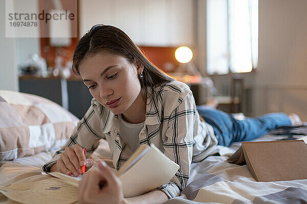 Mädchen studiert Notizen für Prüfung im Bett