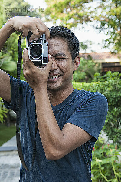 Mann fotografiert mit analoger Entfernungsmesserkamera