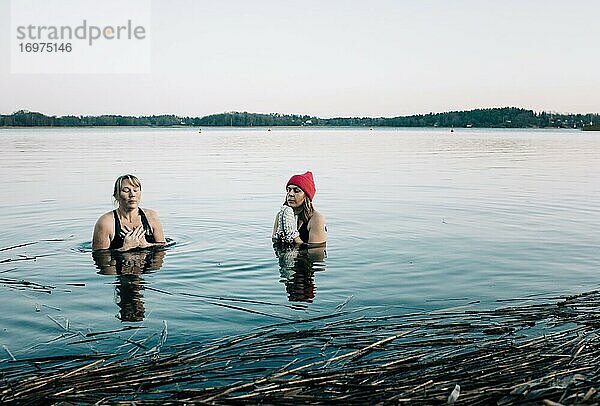 Zwei Frauen im ruhigen nordischen Meer schwimmen im kalten Wasser in Schweden