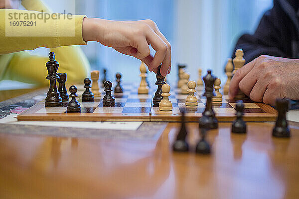 Nahaufnahme eines älteren Mannes und eines Jungen  die zusammen eine Partie Schach spielen