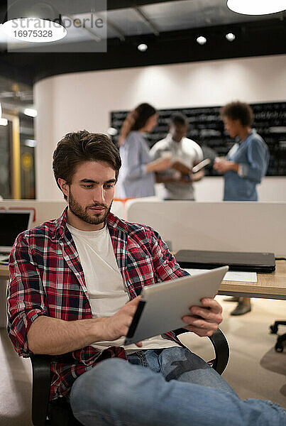 Bärtiger Mann benutzt Tablet im Coworking Space