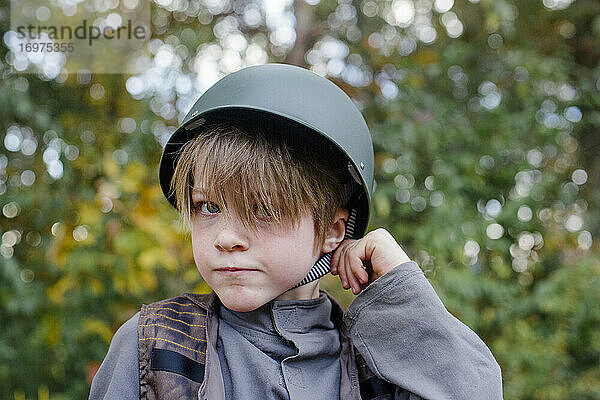 Ein Junge in einem Soldatenkostüm zerrt am Riemen seines Helms