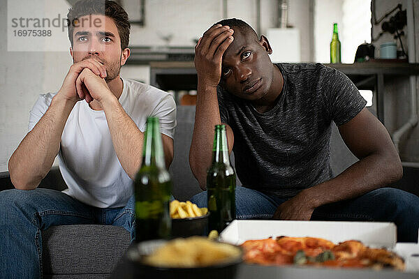 Unglückliche diverse Freunde  die ein enttäuschendes Fußballspiel anschauen