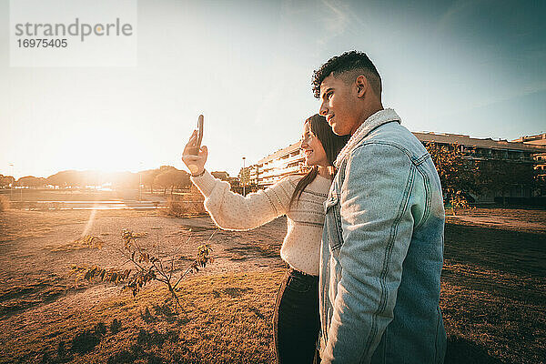 Junges Paar  das ein Selfie mit seinem Smartphone bei Sonnenuntergang macht