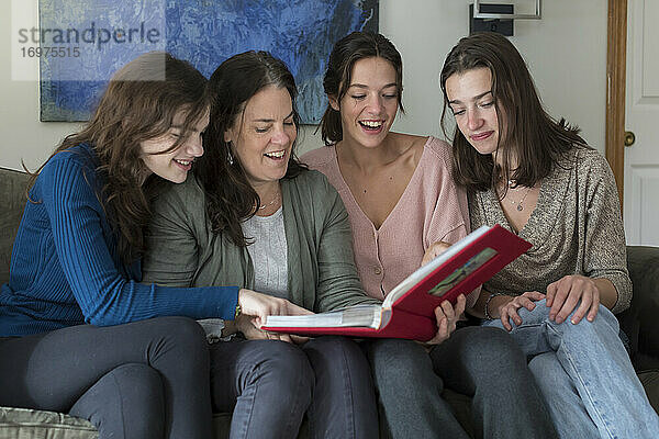 Eine Mutter und ihre drei Töchter lachen beim Betrachten eines Fotoalbums