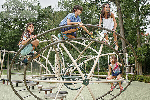 Vier Kinder klettern gemeinsam auf ein Spielgerät auf einem öffentlichen Spielplatz