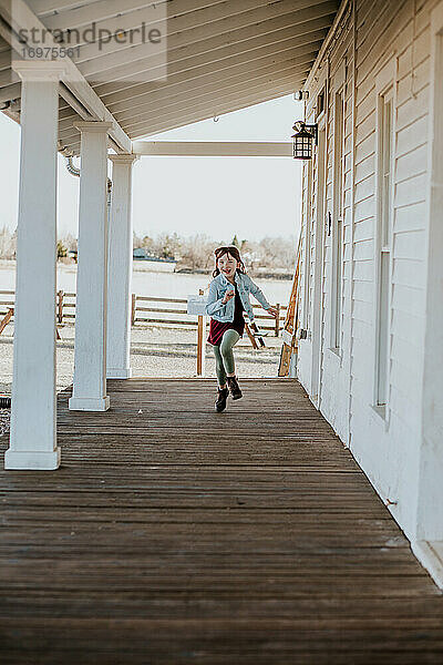 glückliches junges Mädchen  das draußen auf der Terrasse läuft