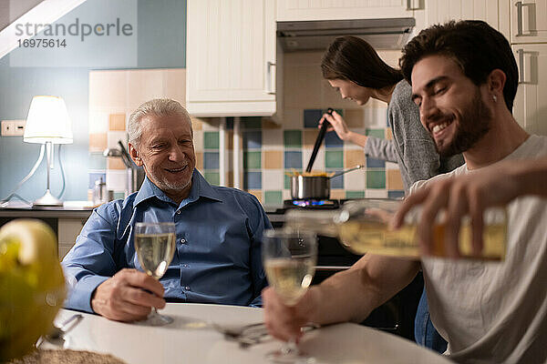 Glücklicher älterer Vater beobachtet Sohn beim Einschenken von Wein