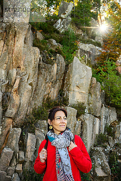 Lachende Wanderin mit Kopftuch und Rucksack  vor Steinformation