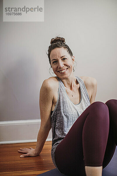 Innenporträt einer lächelnden  sportlichen Frau in Yoga- und Fitnesskleidung