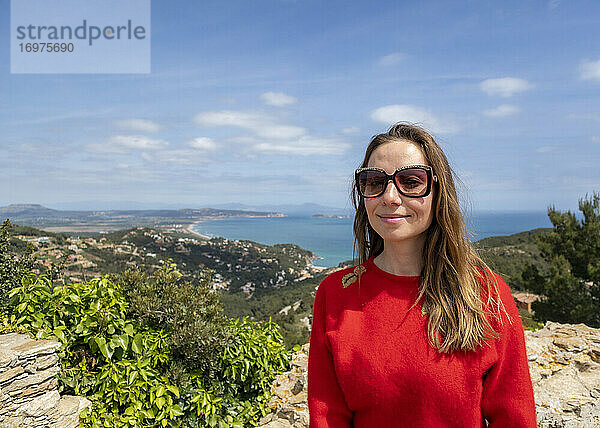 Fröhliches  rot gekleidetes Mädchen  das die Küste genießt und auf das Meer schaut