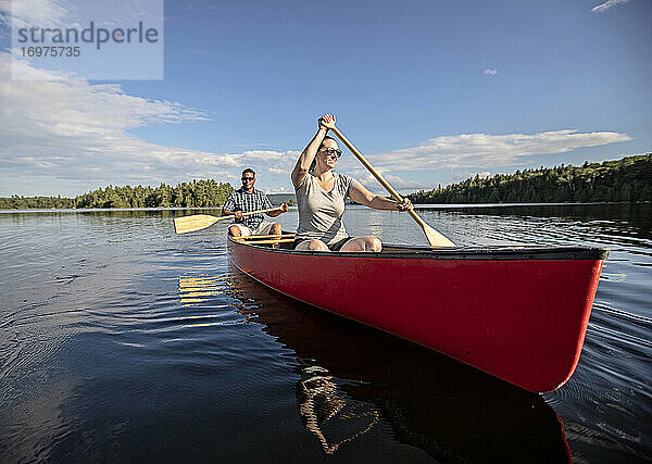 Lächelndes Paar paddelt mit dem Kanu über das ruhige Wasser des Bald Mountain Pond