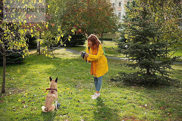 Junge Frau fotografiert Hund im Gras