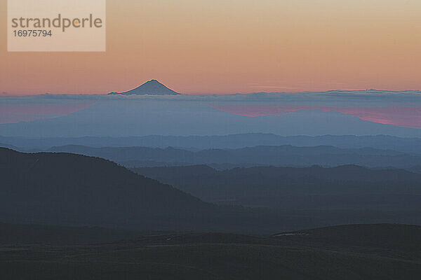 Der Gipfel des Mt Taranaki erhebt sich über die Wolken  während die Sonne hinter dem Horizont untergeht  Tongariro  Neuseeland