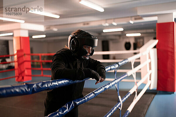Erschöpfter Boxer in Schutzkleidung  der sich auf dem Boxring ausruht