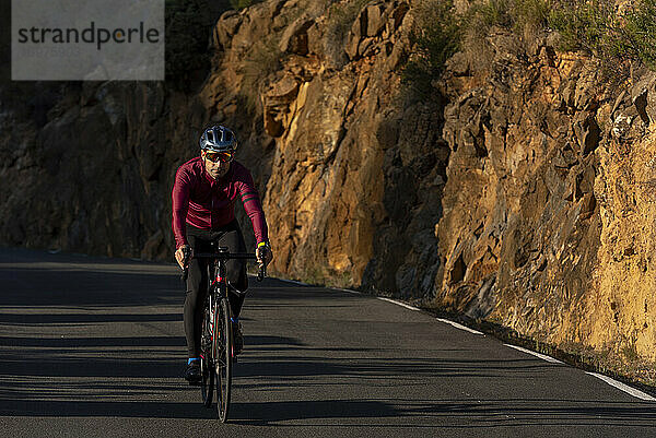 Ein Mann fährt mit dem Fahrrad auf der Bergstraße von Benissa nach Pinos.