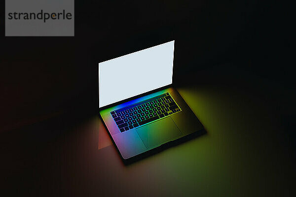 Laptop-Computer mit leuchtenden Farben und hellem Bildschirm bei Dunkelheit