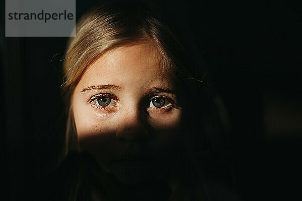 Die Augen eines kleinen Mädchens in hellem Licht mit schwarzem Hintergrund