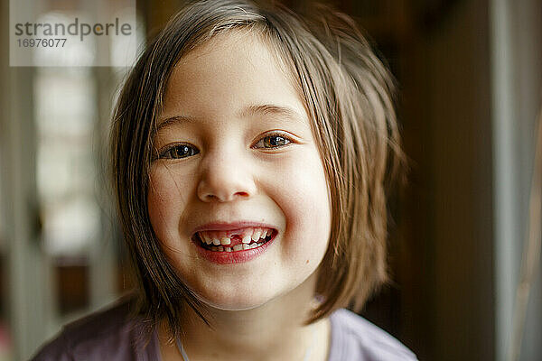 Nahaufnahme eines stolzen kleinen Mädchens  das mit einem breiten Lächeln seinen fehlenden Zahn zeigt