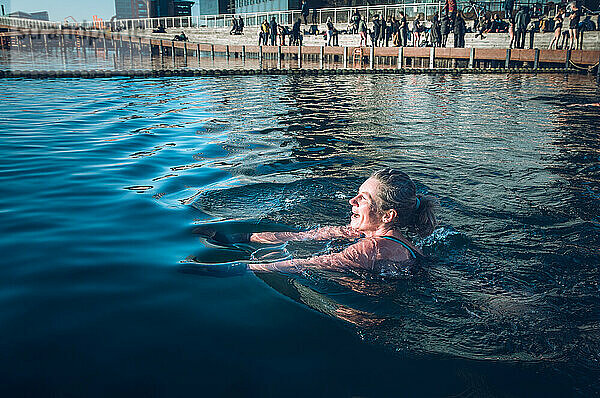 Reife Frau Schwimmen mit Sonnenschein in eiskaltem Wasser in Dänemark