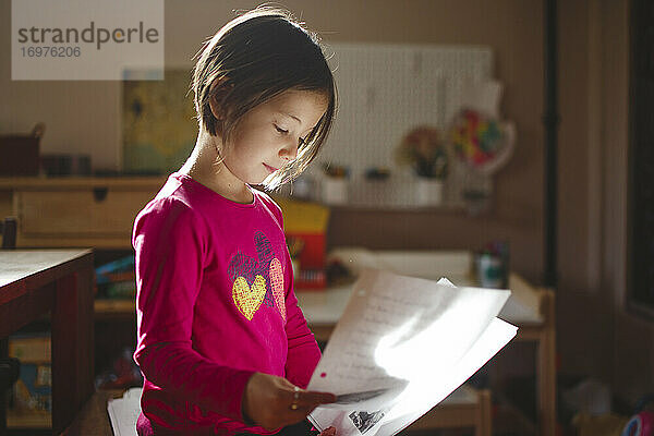 Ein kleines Mädchen in schönem Licht liest von einem Blatt Papier