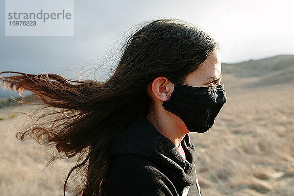 Profilaufnahme eines Tween Girl mit Gesichtsmaske an einem windigen Tag