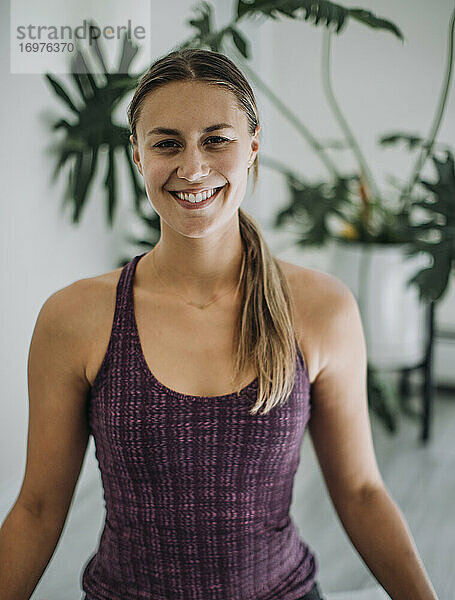 Porträt einer lächelnden jungen Frau in Yoga-Kleidung im Studio