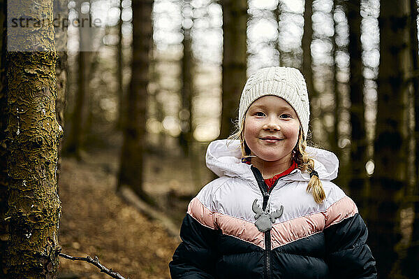 Zufriedenes kleines Mädchen  das tagsüber im Herbstwald chillt
