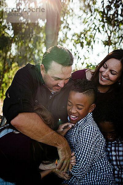 Fünfköpfige Familie umarmt und lacht im Park in Chula Vista